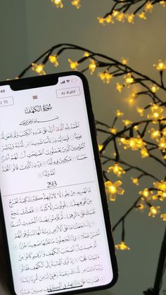 a cell phone with an arabic text on the screen next to a lit up tree