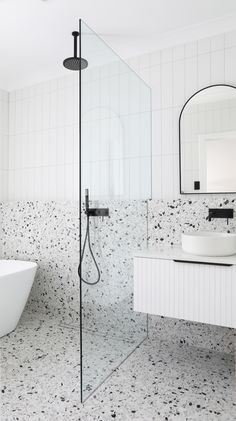 a white bathtub sitting next to a sink in a bathroom under a large mirror