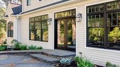 a white house with black windows and stone walkway