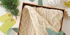 a knitted blanket in a box surrounded by christmas decorations