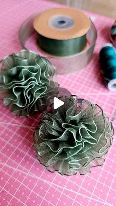 two green flowers sitting on top of a table next to spools of thread