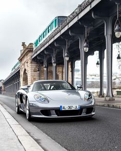 a silver sports car is driving down the road in front of a large building with columns