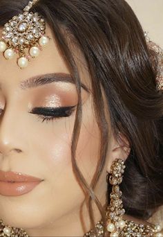 a close up of a woman with makeup and jewelry on her face, wearing a head piece