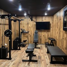 a home gym with wooden walls and flooring is shown in this image, there are several exercise equipment set up on either side of the wall