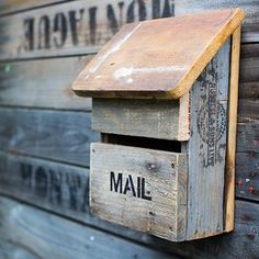 a mailbox mounted to the side of a wooden building that says mail on it