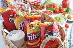 a basket filled with chips and dips next to other foods