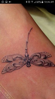 a dragonfly tattoo on the back of a woman's leg