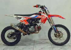 a red and white dirt bike parked on top of a tile floor next to a wall