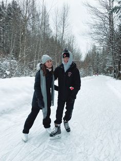 two people are standing in the snow on skis and one is holding onto another person's hand