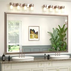 a bathroom with two sinks and a large mirror on the wall next to a potted plant