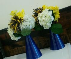 two blue vases with yellow and white flowers in them sitting on a counter top