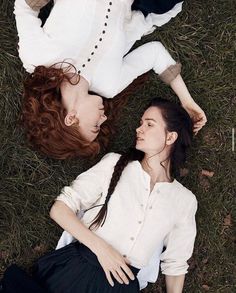 two young women laying on the ground next to each other, one with red hair