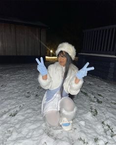 a woman sitting in the snow with her hands up and two fingers out, making peace signs