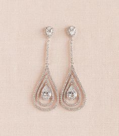 two pairs of earrings with tears and cubicles on the bottom, one in white gold