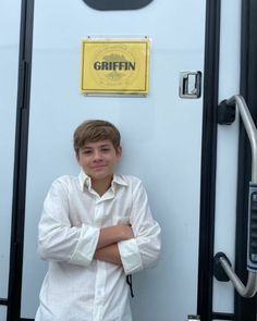 a young man is standing in front of a door with his arms crossed and looking at the camera