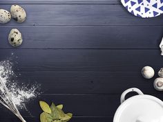 an arrangement of eggs, flour and other ingredients on a black table with blue background