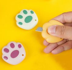 a hand is holding a small plastic object with paw prints on it, next to another toy