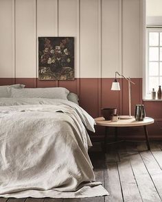 a bed sitting in a bedroom next to a table with a lamp on top of it