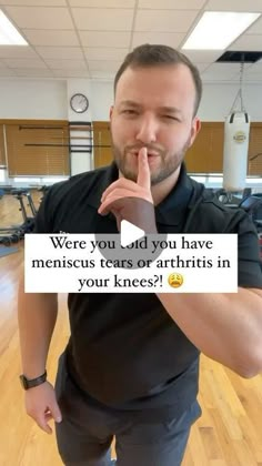 a man standing in an empty gym holding his finger to his mouth and making a funny face