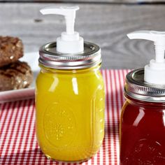 two mason jars with soap dispensers are sitting on a table next to hamburgers