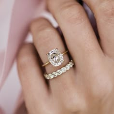 a woman's hand with two wedding rings on her left and the other hand holding an engagement ring