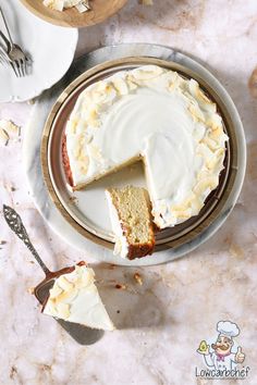 a cake with white frosting sitting on top of a plate next to a knife and fork