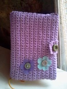 a crocheted book with buttons and flowers on the front is sitting on a window sill