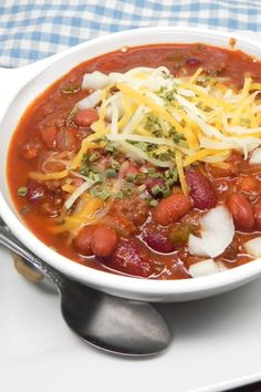 a white bowl filled with beans and cheese on top of a plate next to a fork