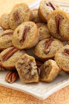 a white plate topped with muffins and pecans on top of a table