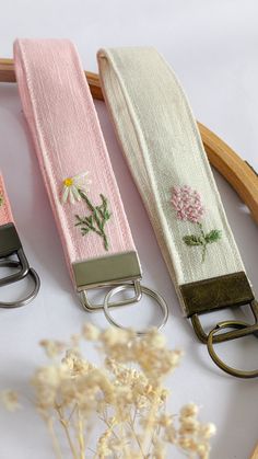 three key chains with embroidered flowers on them