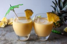 two glasses filled with orange juice and garnished with pineapple