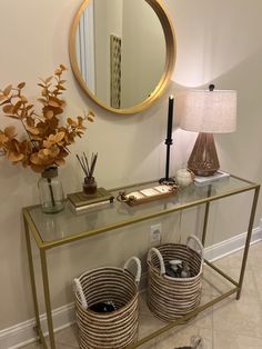 two wicker baskets under a table with a mirror and lamp next to each other