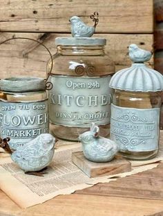 an old fashioned kitchen canisters are sitting on a table with some bird figurines