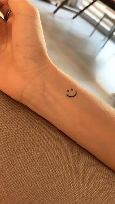 a small smiley face tattoo on the wrist