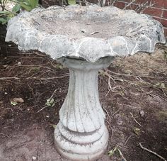 an old bird bath sitting in the dirt