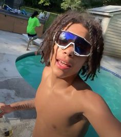 a shirtless man wearing sunglasses near a swimming pool