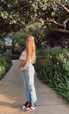 a woman standing on a sidewalk with her hands in her pockets and looking off to the side