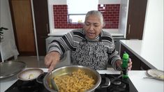 an old man is cooking food in a pan on the stove with a green bottle next to him