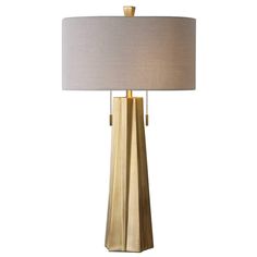 a table lamp with a white shade on it and a gold base, sitting against a white background