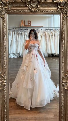 a woman taking a selfie in front of a mirror wearing a white wedding dress