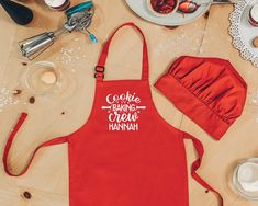 a red apron with the words cookie baking crew hannah printed on it next to other kitchen items