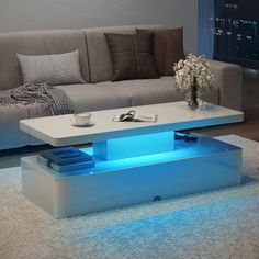 a living room with a couch, coffee table and blue lights on the bottom shelf