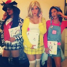 three women dressed in costumes standing next to each other and one is holding a cell phone