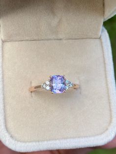 an engagement ring with a tan cushion cut stone and three diamonds on the side in a velvet box