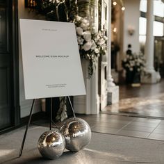 two shiny disco balls sitting next to a welcome sign