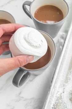 two cups of hot chocolate and marshmallows on a white marble countertop