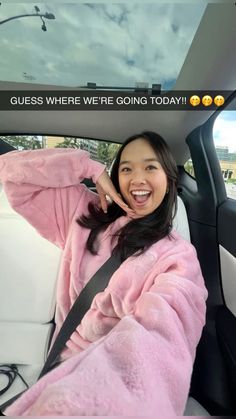 a woman sitting in the back seat of a car wearing a pink robe and smiling