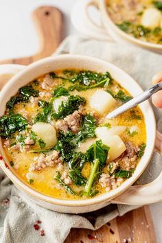 two bowls of soup with meat, spinach and potatoes