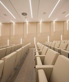 an empty auditorium with rows of seats and lights on the ceiling is lit by recessed lighting