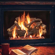 an open book is sitting in front of a fireplace with fire and logs on the floor